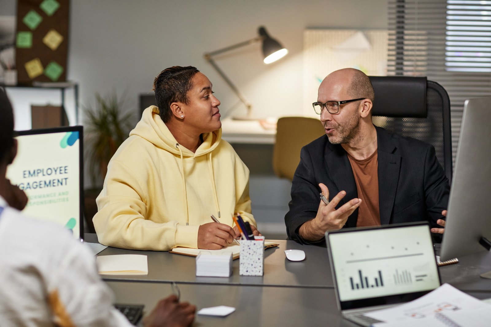 Portrait of mature businessman talking to female colleague in office during team meeting at night